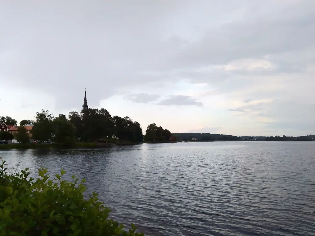 Denna bild är tagen under en regning dag från stranden på Loppholmarna. På bilden ser en Kyrkan, Strandpromenaden och Lindesjön.