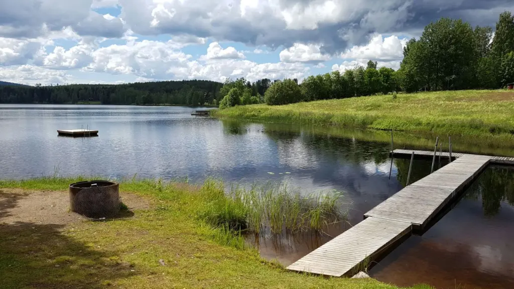 Bilden visar del av Skidtjärnnen sett från Lillviksbadet i sydvästlig riktning. I förgrunden till vänster grillplats och till höger en del av badbryggan. Längre